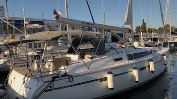 A white yacht named 'Cruiser 46' docked at a marina with other boats, a clear sky, and a building in the background.