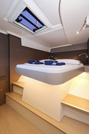 A modern bedroom with a skylight, a bed with neatly folded towels, and a built-in bedside table. - Sibenik Sun and Beach Sailing Extravaganza: A Croatian Coastal Adventure (Vodice)