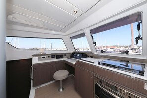 A compact galley with a single bar stool, a stove, and a control panel. - Sibenik Sun and Beach Sailing Extravaganza: A Croatian Coastal Adventure (Vodice)