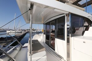 Ein Yachthafen mit vertäuten Booten, ein überdachter Bereich mit Sitzgelegenheiten und freier Wasserblick.
