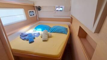 A compact bedroom with a single bed, a small window, and a mounted television.