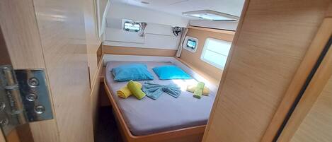 A compact, well-lit room with a bed, pillows, and towels.