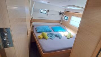 A compact bedroom with a bed, two pillows, and a small window.