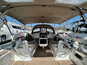 Das Deck eines Bootes mit Steuer, Bedienfeld und Sitzgelegenheiten.
