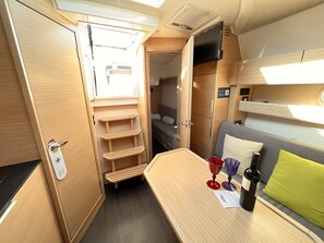 A compact RV interior with a kitchenette, a small seating area, and a TV mounted on the wall. - Sun-Kissed Sailing Adventure in Zadar, Croatia (Biograd na moru)
