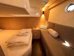 A compact cabin with two beds, a small table, and a wall-mounted light fixture. - Sun-Kissed Sailing Adventure in Zadar, Croatia (Biograd na moru)