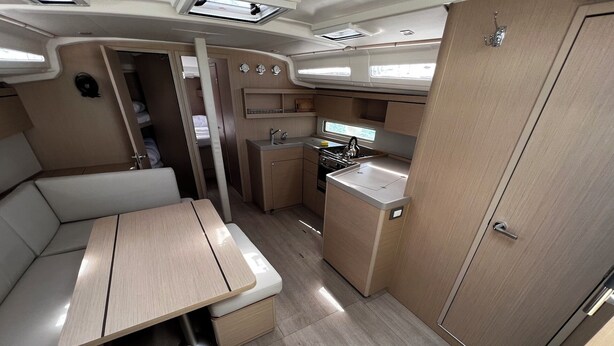Interior compacto de una caravana con kitchenette, zona de comedor y un pequeño espacio para dormir.