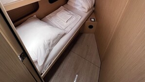 Una cama individual con ropa de cama blanca y cabecera de madera.