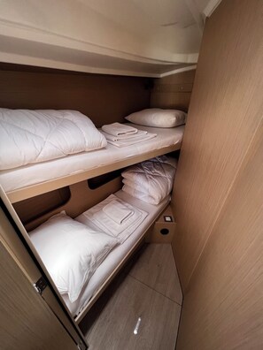 Ein Stockbett mit weißer Bettwäsche und einem hölzernen Kopfteil.