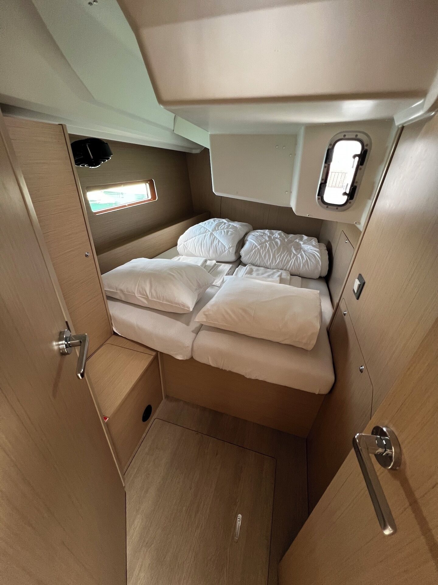 A compact, well-lit interior with a bed, a small window, and a door.