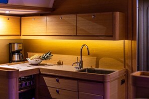 A compact kitchen with wooden cabinets, a stainless steel sink, and a coffee maker. - Sun-Kissed Sailing Adventure in the Ionian Islands, Lefkada (Lefkada)