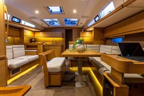 A compact, well-lit interior with a dining area, seating, and a laptop on a table. - Sun-Kissed Sailing Adventure in the Ionian Islands, Lefkada (Lefkada)