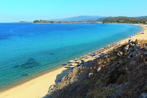A coastal beach with clear blue water, sandy shore, and rocky terrain. - Macedonian Sun and Beach Sailing Extravaganza (Sithonia)