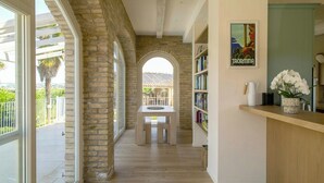 Um corredor com parede de pedra, uma mesa de madeira e uma estante de livros.