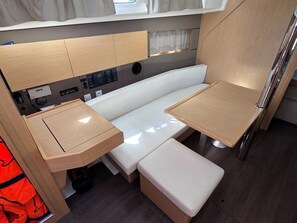 Ein kompaktes, modernes Wohnmobil-Interieur mit einer Küchenzeile, einer Sitzbank und einem kleinen Tisch.