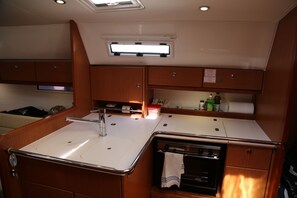 Una kitchenette compacta con estufa, lavamanos y armarios para guardar.