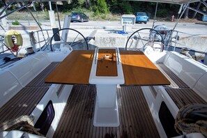 A boat's deck with a central table, steering wheel, and life preserver. - Sun-Kissed Sailing Adventure in Istria, Croatia (Pula)