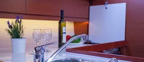 A kitchen with stainless steel sinks, a potted plant, and wine glasses.