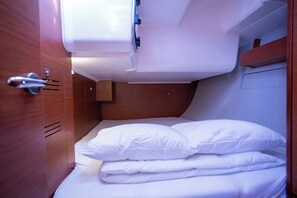Cabana petita i ben il·luminada amb un llit individual, un petit armari de fusta i una porta amb manilla.