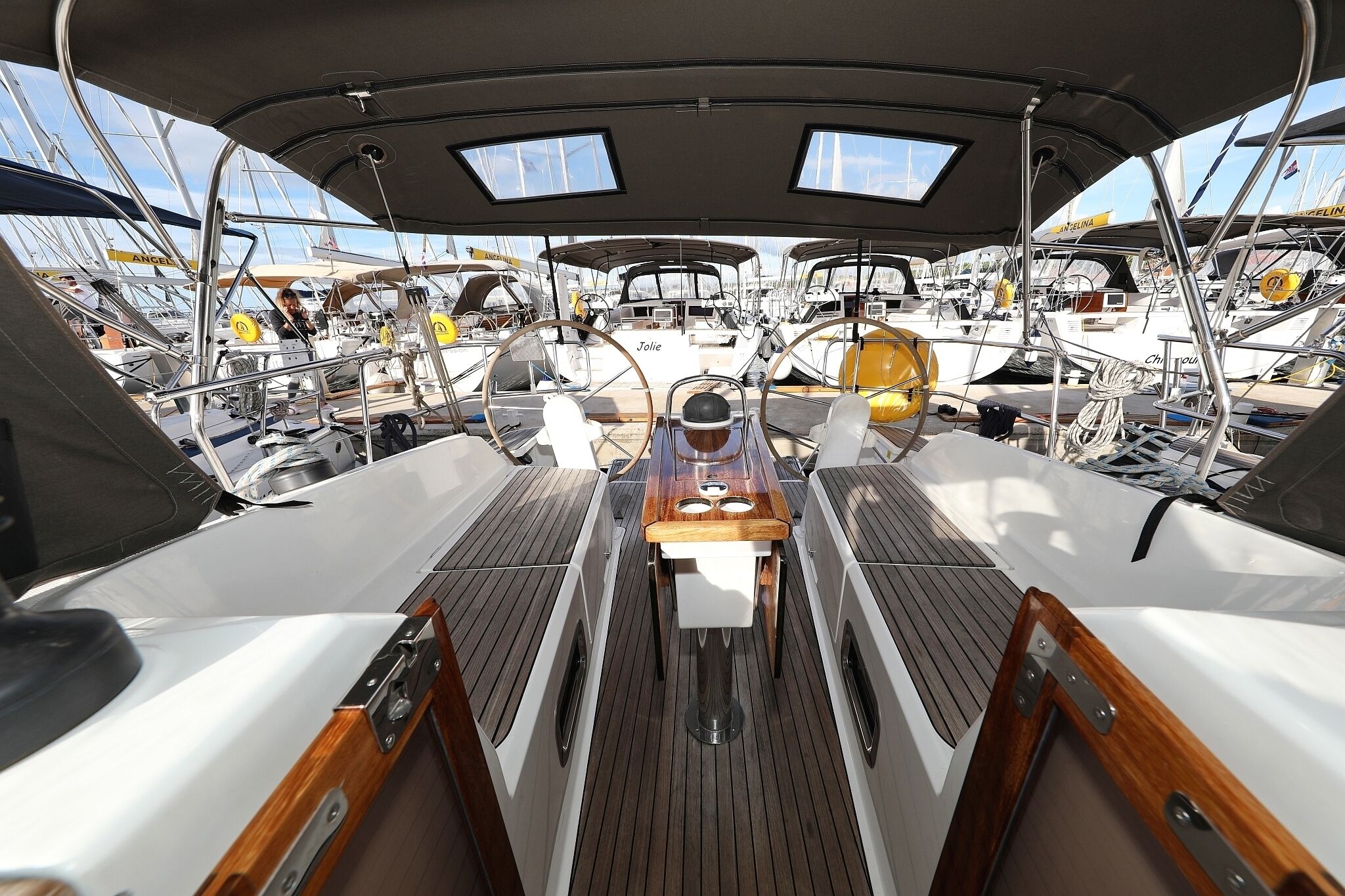 A boat deck with a central table, multiple chairs, and a steering wheel.