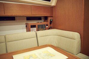 A cabin with a cushioned seating area, a control panel, and a map on the table. - Sun-Kissed Sailing Adventure in Istria, Croatia (Pula)