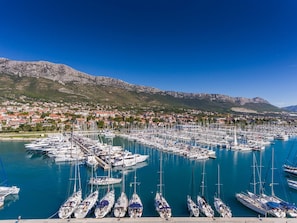 Ein Yachthafen mit zahlreichen Booten, eine Stadt im Hintergrund und Berge.