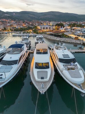 A marina with several yachts docked, a waterfront view, and a distant cityscape. - Sun-kissed Sailing Adventure in Split-Dalmatia, Croatia (Seget Donji)