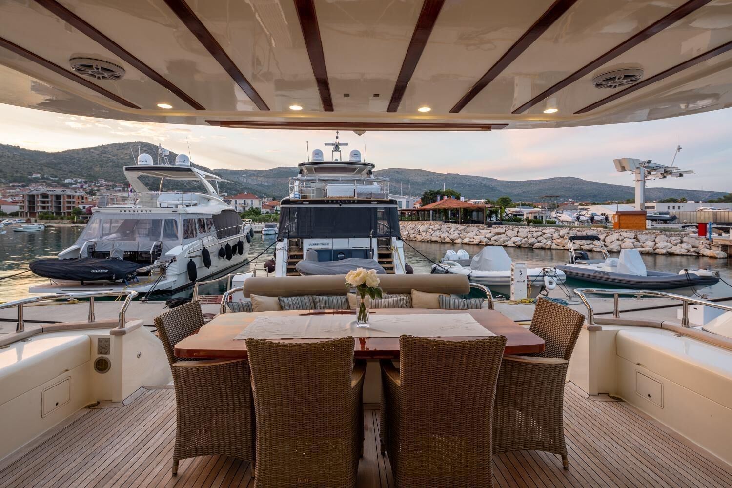A yacht deck with a dining area, lounge chairs, and a view of the marina.