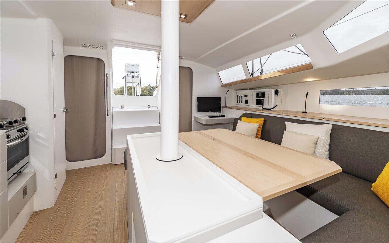 Un intérieur de camping-car compact comprenant un coin cuisine, un espace repas et un coin salon.