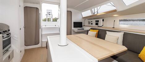 Interior compacto de autocaravana con kitchenette, comedor y zona de estar.