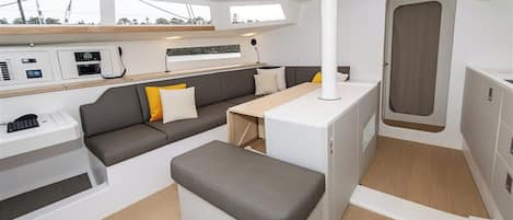 A compact, modern interior with a sofa, bench, and kitchenette area.