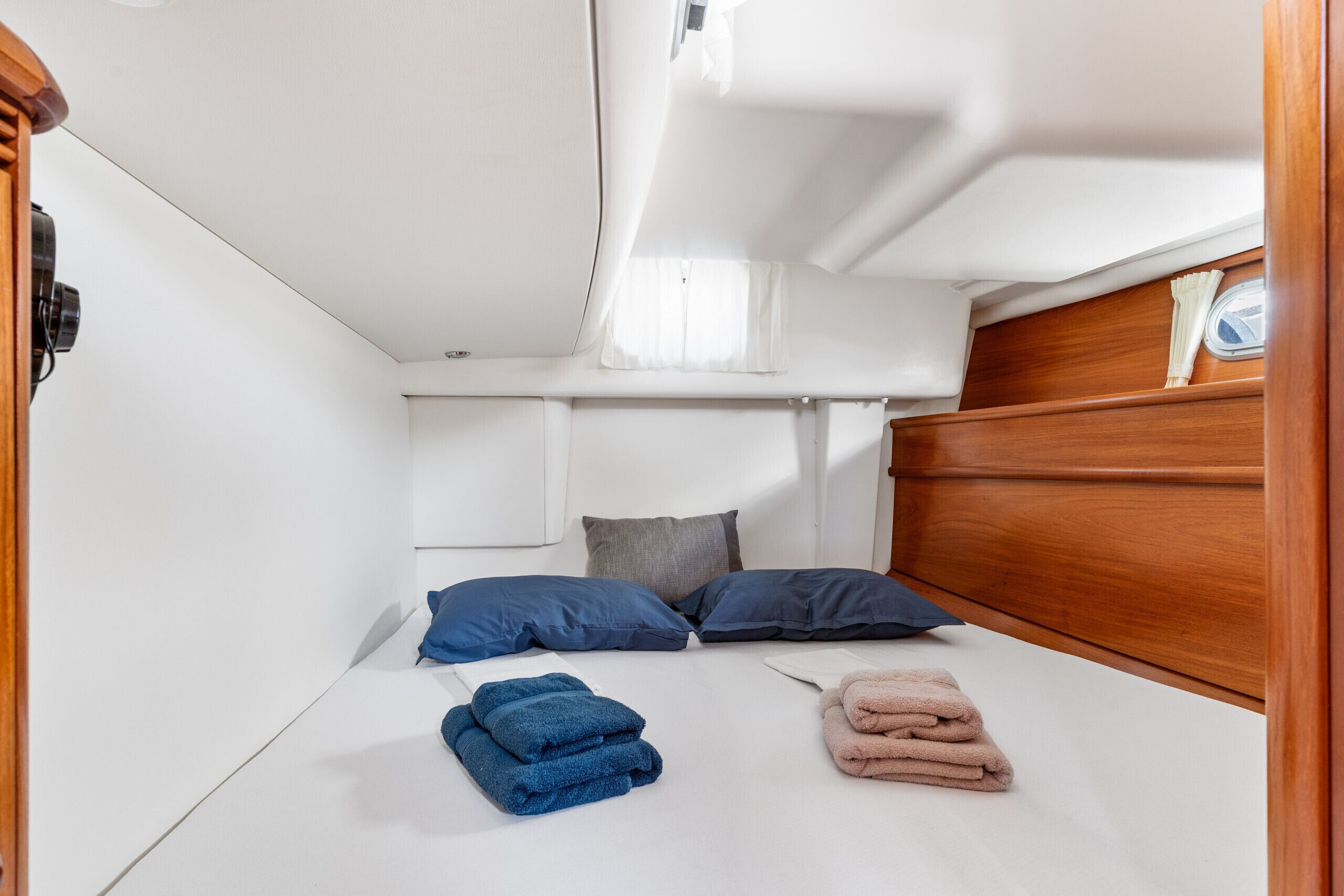 Ein kleines, helles Blockhaus mit einem Bett, Kissen und ordentlich gefalteten Handtüchern.