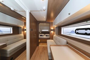 Ein kompaktes Wohnmobil-Interieur mit Bett, Sitzgruppe und einem Fenster zur freien Fahrt.