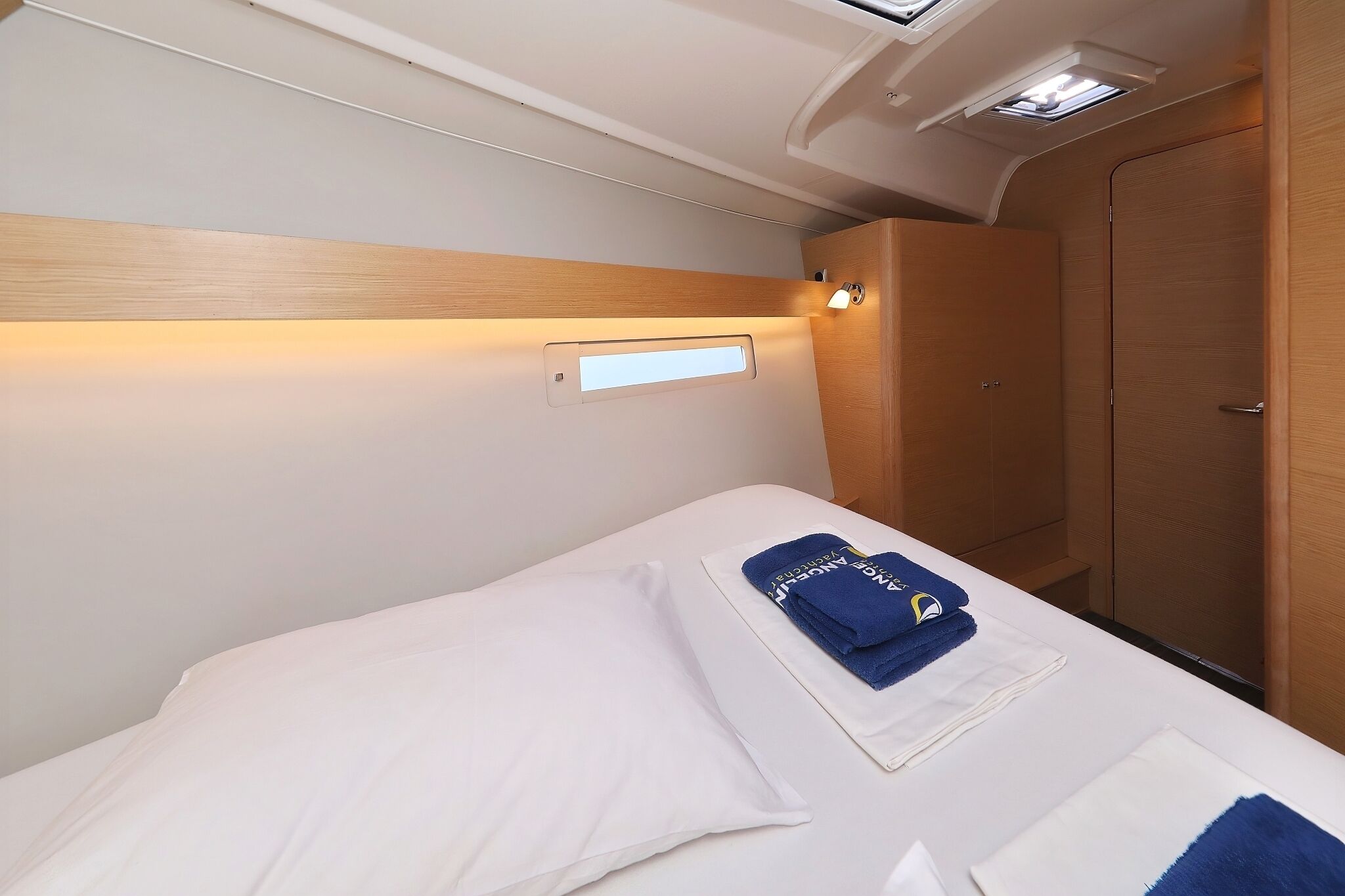 Una habitación de hotel con cama, armario, mesita de noche y lámpara fijada a la pared.