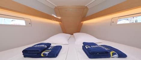 A narrow train compartment with two beds, each with a folded blue towel and a pillow.