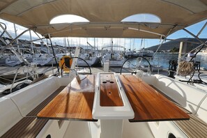 A boat deck with a wooden table, white railings, and a canopy overhead. - Sun-kissed Sailing Adventure in Split-Dalmatia, Croatia (Trogir)