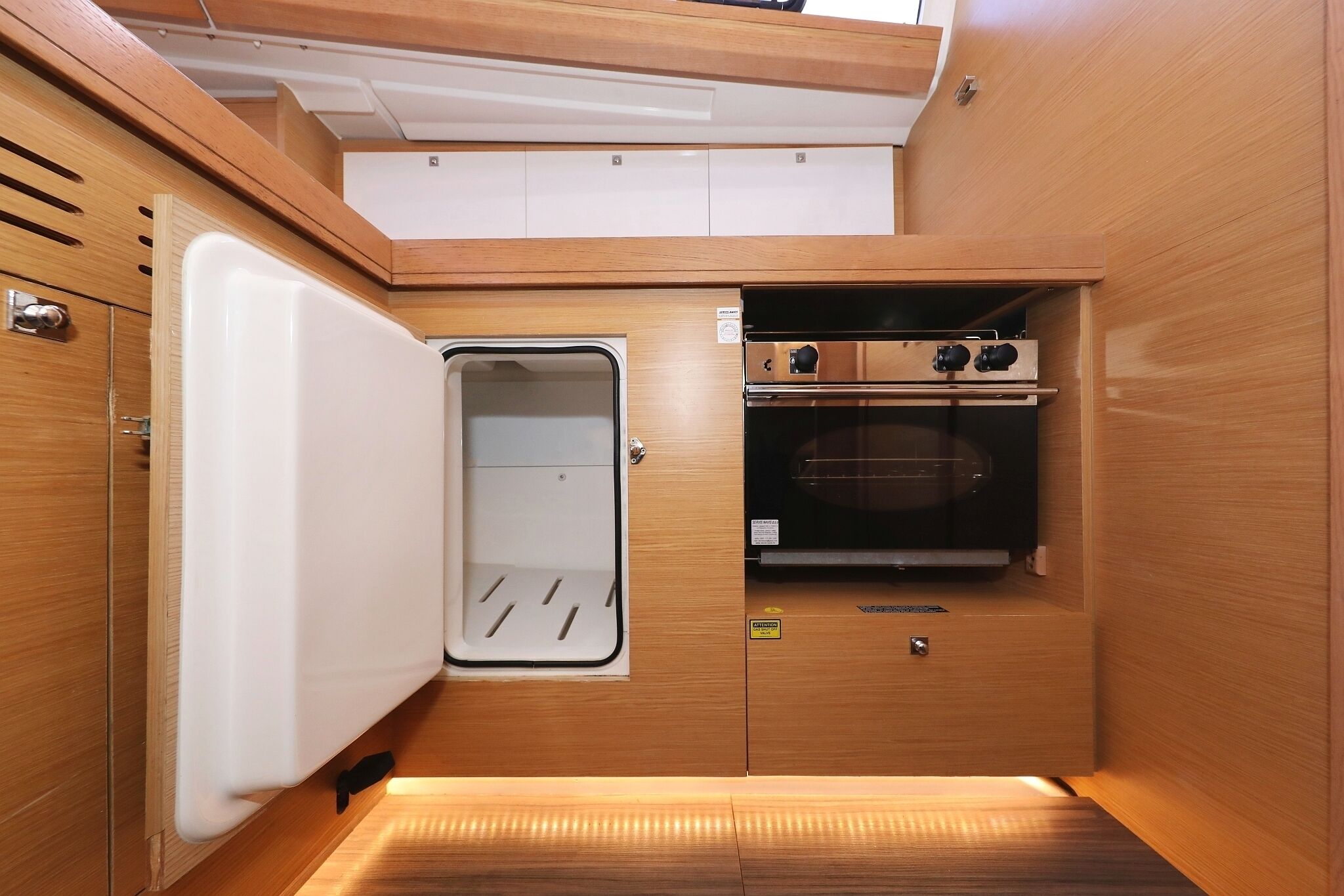 A compact kitchen with a refrigerator, oven, and a small pantry.