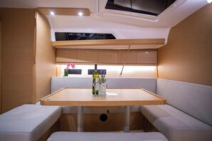 A compact kitchen area with a wooden table, seating, and built-in cabinets. - Sun-Kissed Sailing Adventure in Istria, Croatia (Pula)
