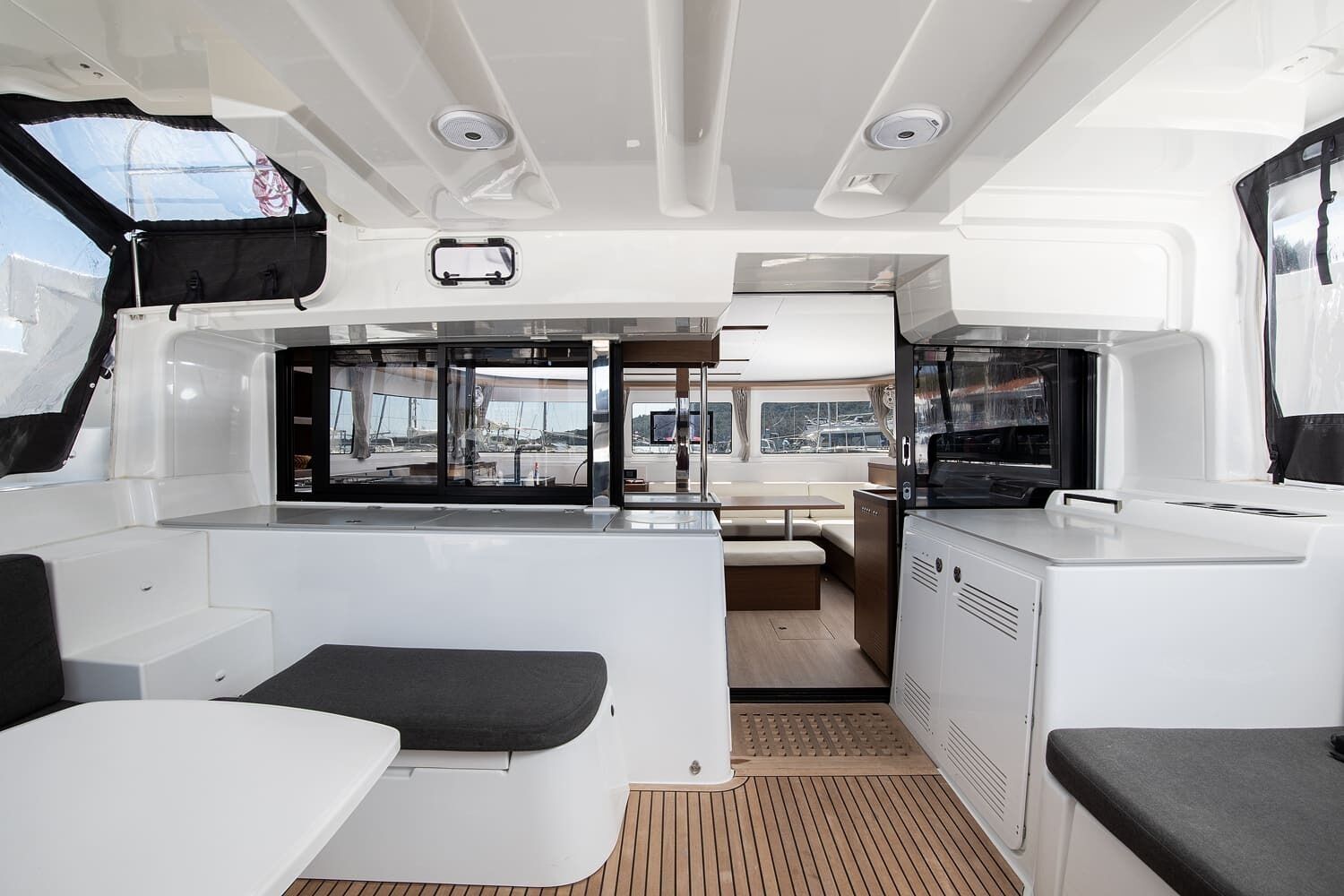 A boat's interior with a dining area, kitchen, and seating.