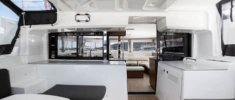 A boat's interior with a dining area, kitchen, and seating.