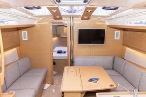 A compact, well-lit interior with a central table, cushioned seating, a mounted TV, and skylights. - Sun-Kissed Sailing Adventure in Sibenik, Croatia (Primošten)