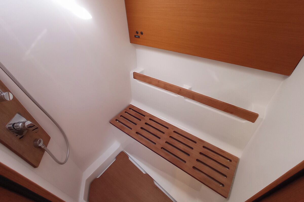 A bathroom with a wooden vanity, a sink, and a shower area.