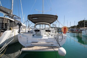 A sailboat docked at a marina with a covered deck area, a steering wheel, and a winch. - Sun-kissed Sailing Adventure in Istria, Croatia (Pomer)