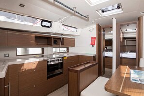 A compact kitchen with a stove, sink, and wooden cabinets. - Sun-kissed Sailing Adventure in Istria, Croatia (Pomer)