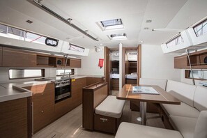 A compact galley with a stove, sink, and storage cabinets. There is a small seating area with a table and cushioned bench.