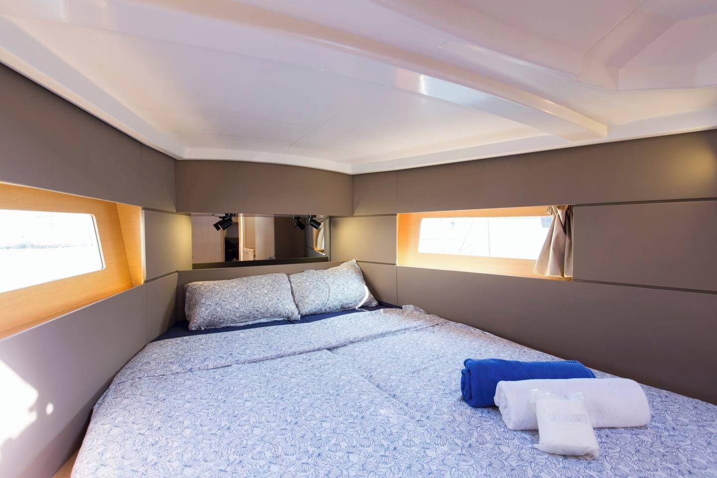 Une chambre à coucher avec un lit, deux fenêtres, un miroir et une petite fenêtre située au-dessus du lit.