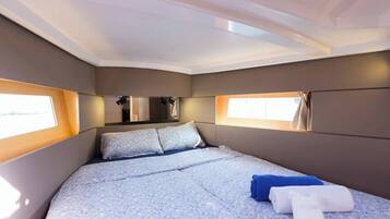 Une chambre à coucher avec un lit, deux fenêtres, un miroir et une petite fenêtre située au-dessus du lit.