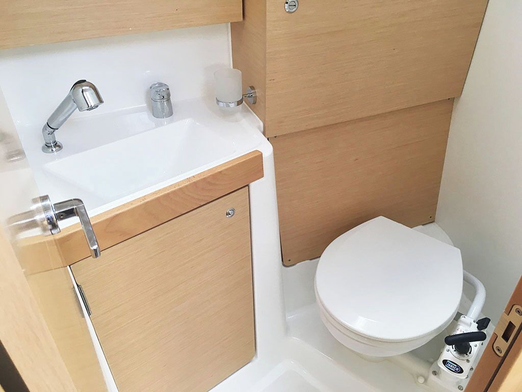Un baño pequeño con un lavamanos blanco, un inodoro y un armario de madera.