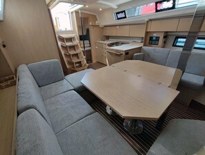 Ein gemütlicher Innenraum mit Esstisch, gepolsterten Sitzmöglichkeiten, einer Küchenzeile und einem Fernseher.