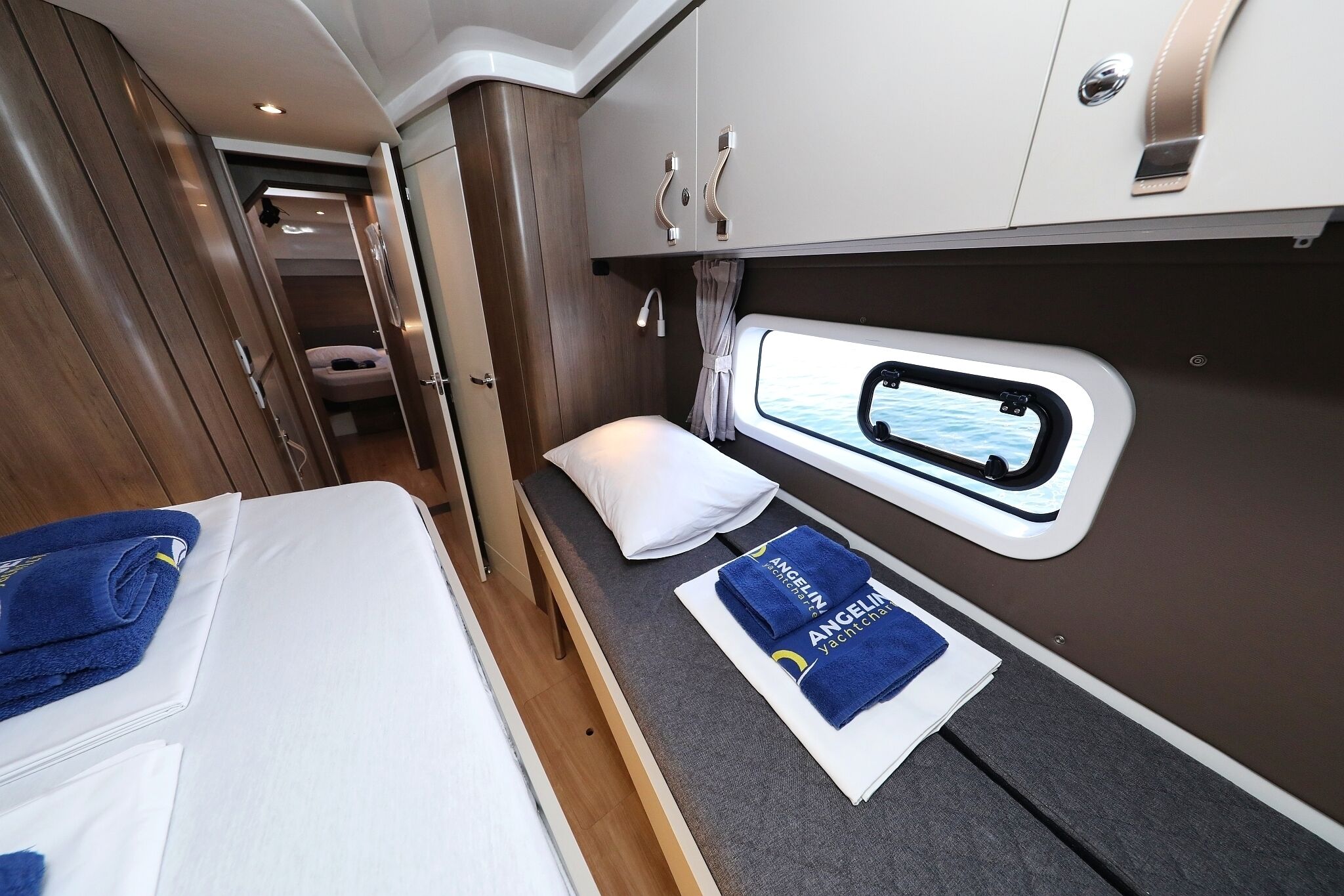 A compact, well-lit interior with a bed, a small seating area, and a window providing a view.